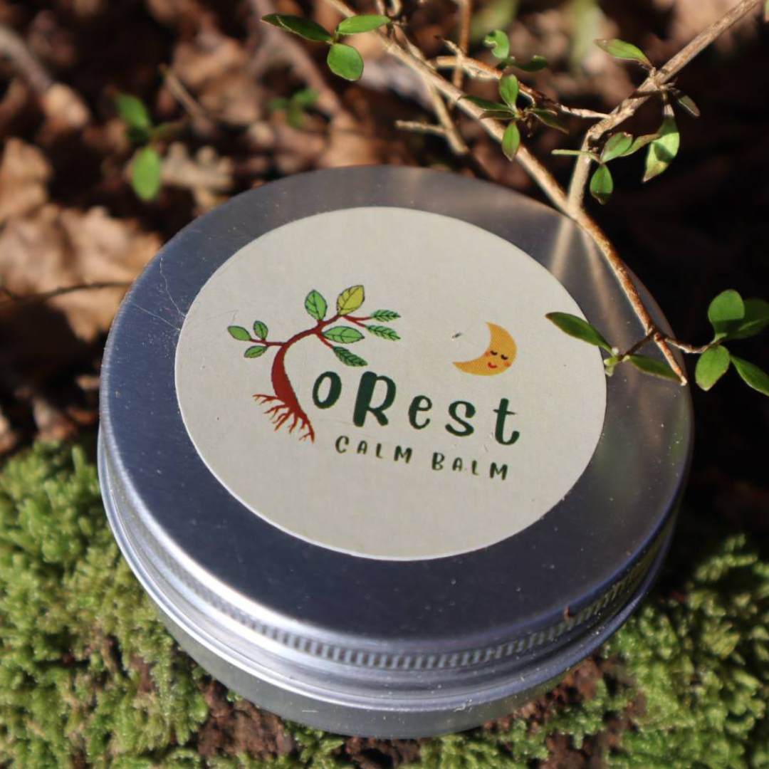 Container of 'oRest Calm Balm' on a natural background with greenery.