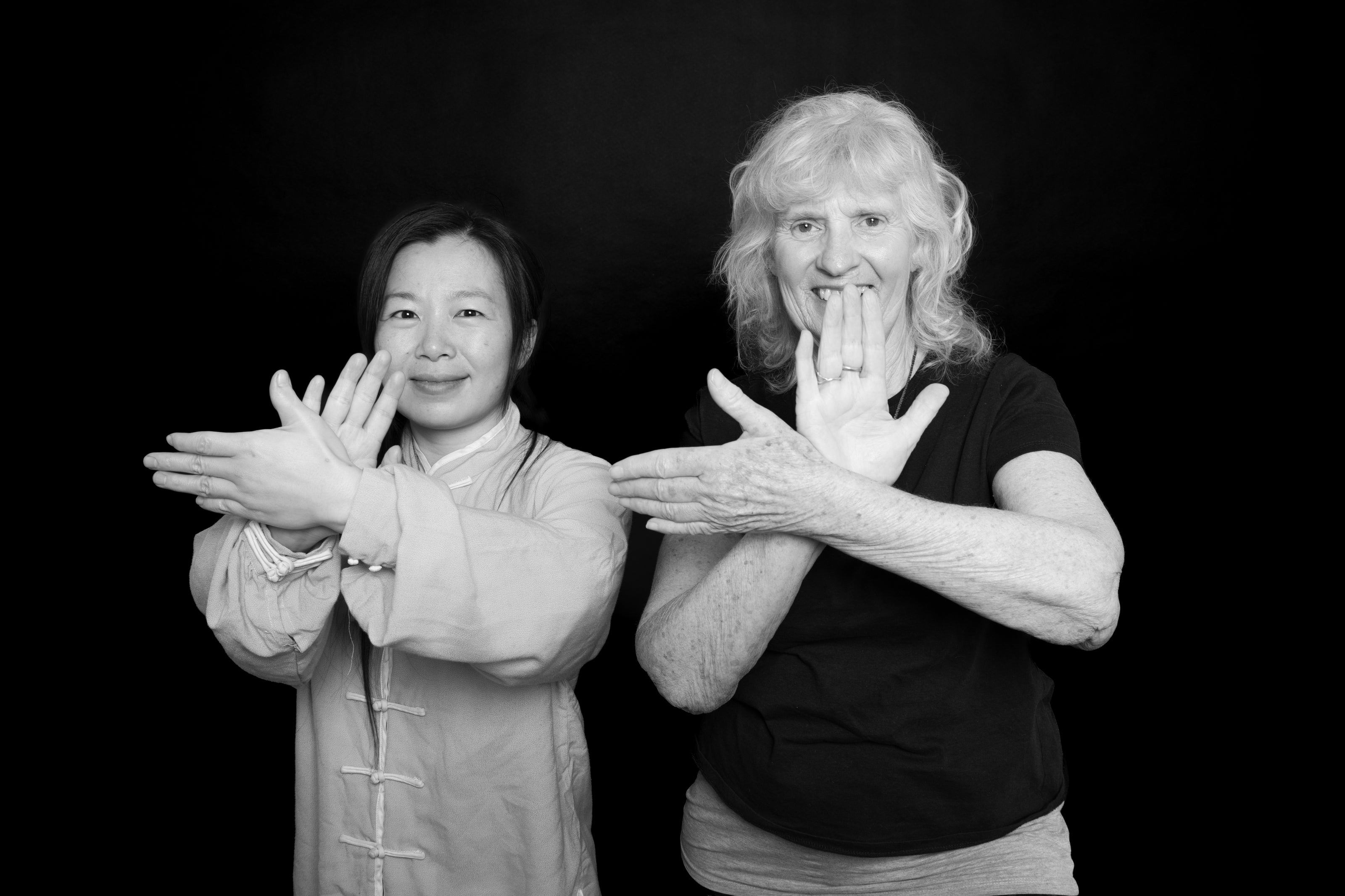 Jingjing and her student demonstrating a Tai Chi stance against a black background